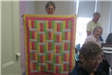 Woman Holding Yellow, Pink, and Green Quilt
