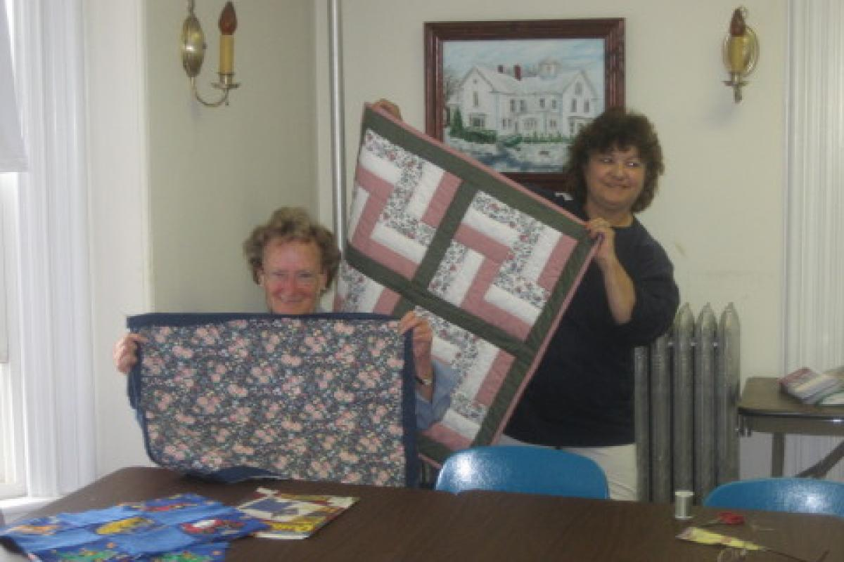 Two Women Holding Quilts