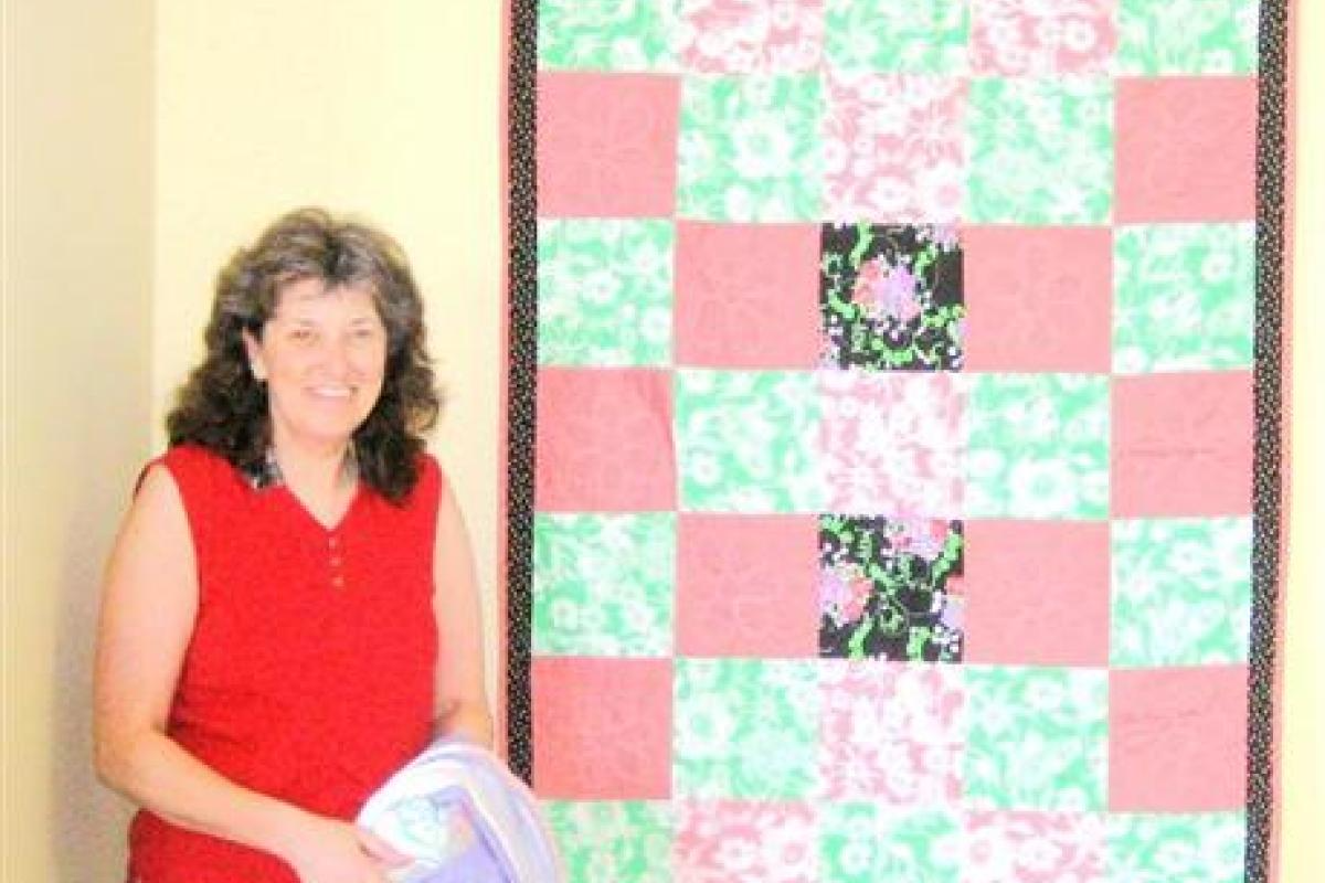 Woman Standing Next to Red and Green Quilt