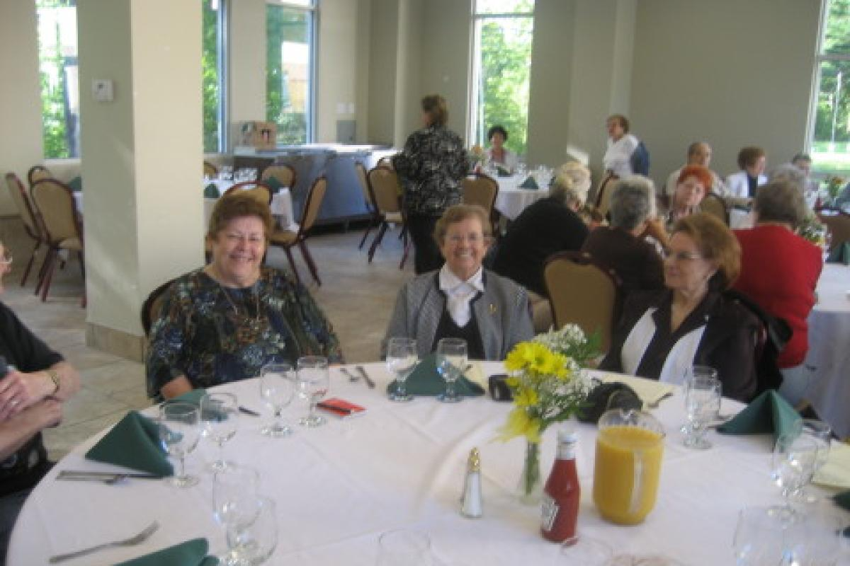 Three Women Sitting at a Table Smiling